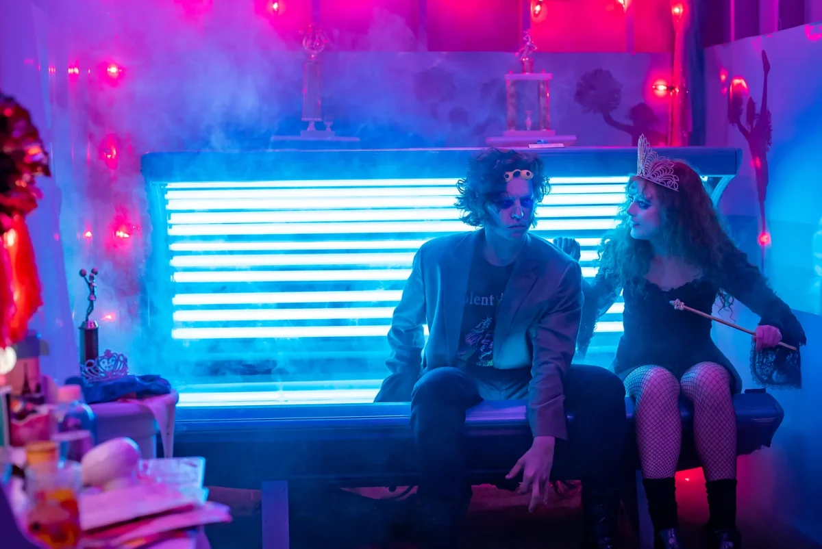 The Corpse, portrayed by Cole Sprouse, and Lisa Swallows, portrayed by Kathryn Newton, sitting on a 80s tanning bed. Photo by Michael K. Short via Focus features.