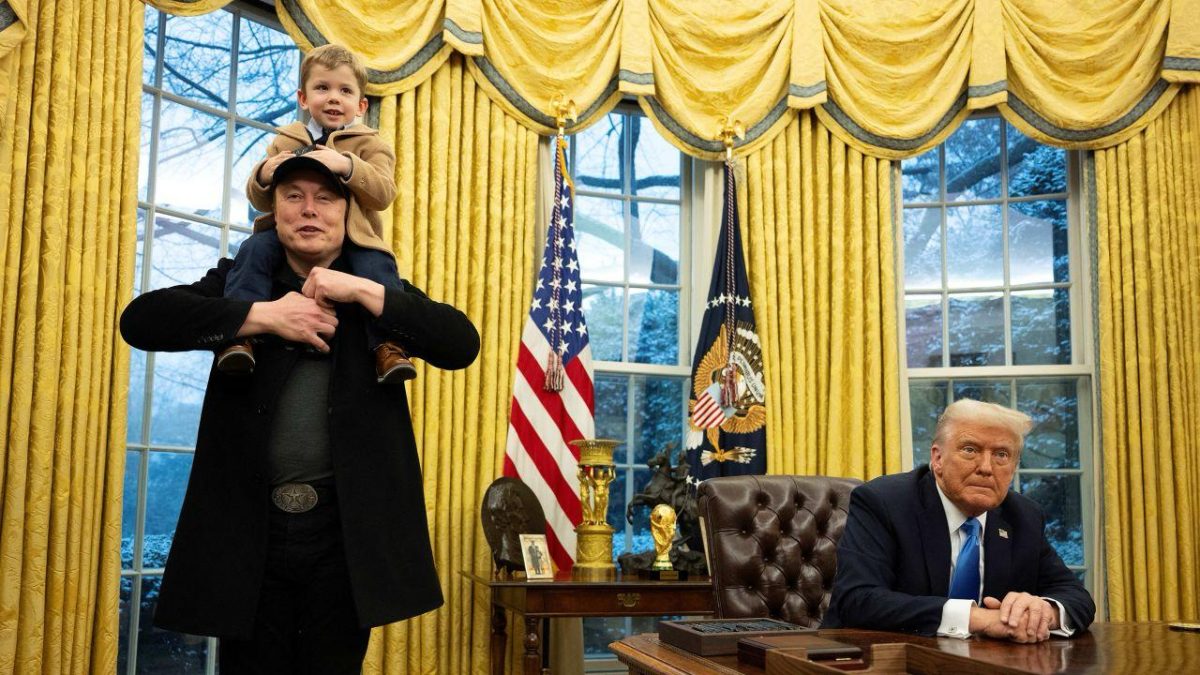 Elon Musk carries his son on his shoulders while speaking as President Trump looks on in the oval office of the White House